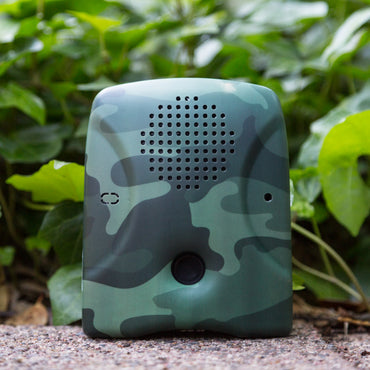 The Dog Silencer MAX with camouflage faceplate up against foliage