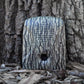 The Dog Silencer MAX with the tree bark faceplate attached up against a tree to show the camouflage effect 
